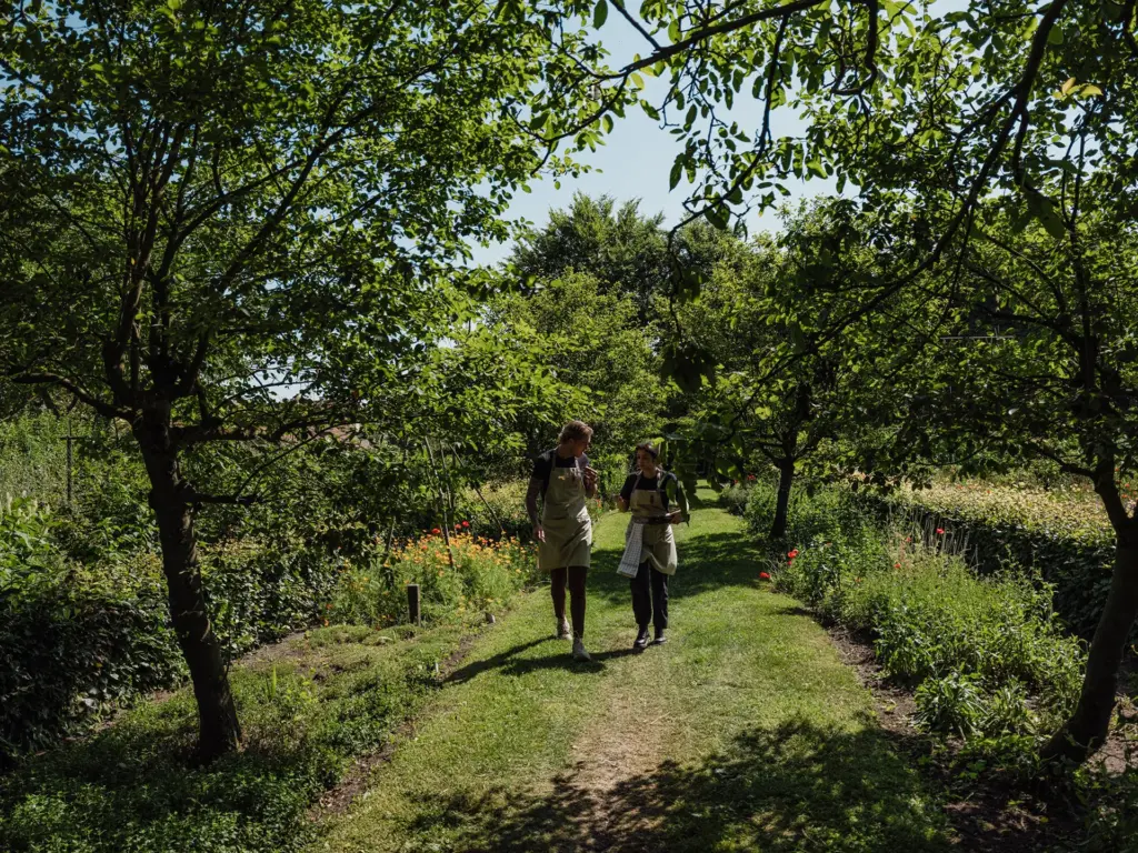 Twee gasten wandelen over een graspad door een bosrijke kasteeltuin