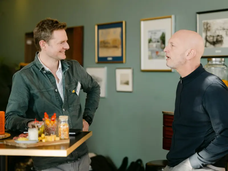 Twee mannen in gesprek bij een statafel op het kantoor van Tool2Match