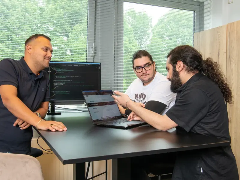 Drie van onze developers overleggen aan tafel over een koppeling